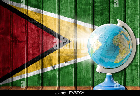 Globo con una mappa del mondo su un sfondo di legno con l'immagine della bandiera della Guyana. Il concetto di viaggio e il tempo libero all'estero. Foto Stock