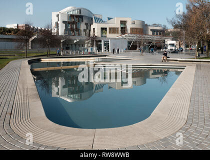 Vista su un lago al di fuori dell'edificio del Parlamento scozzese a Holyrood a Edimburgo in un giorno nuvoloso Foto Stock