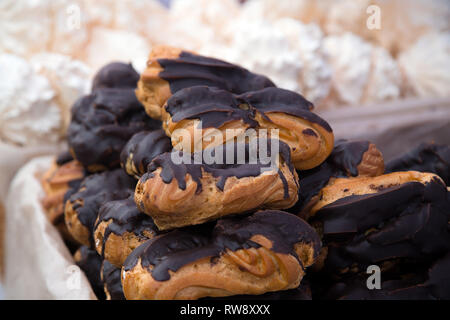 Grappolo di pasticceria ecler ricoperti di cioccolato impilati nella parte superiore di ogni altro a mercato alimentare Foto Stock
