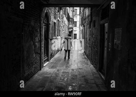 Un uomo a piedi una una stradina di Venezia. Strade di Venezia, Veneto, Italia Foto Stock