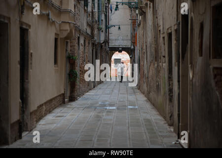 Un uomo a piedi una una stradina di Venezia. Strade di Venezia, Veneto, Italia Foto Stock