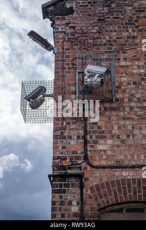 Due telecamere di sicurezza sulla fine di un edificio sia rivolte in direzioni differenti Foto Stock