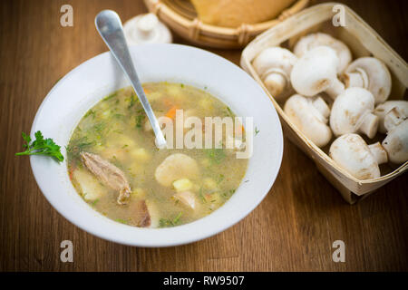 In casa rurale con la zuppa di verdure e funghi in una ciotola su una tavola di legno Foto Stock