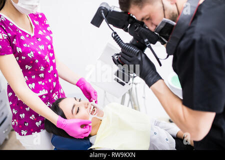 Chiusura del giovane dentista sta immagine della bocca, il suo lavoro sui denti del paziente femmina. Foto Stock