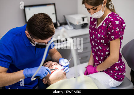 Dentista maschio con assistente esaminando le ragazze di denti in sedia dentisti Foto Stock