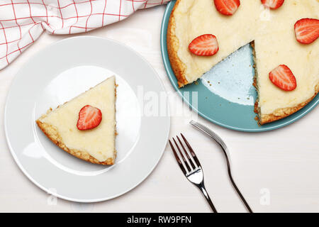 Classic cheesecake con fragole su uno sfondo bianco. Un pezzo su una piastra. Vista dall'alto. Foto Stock