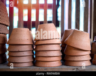 Pile di vasi di terracotta sul vecchio scaffale di legno nei locali di vaso in terracotta fabbrica. Foto Stock