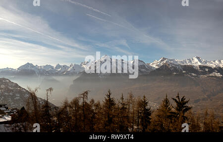 Alte cime coperte di neve e le montagne e il misty valle delle Alpi del Vallese della Svizzera. Foto Stock