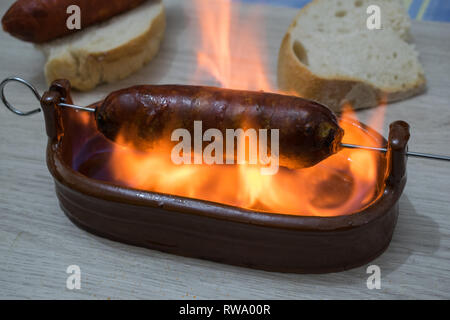 Il chorizo ​​al infierno, piatto tipico della cucina spagnola. Il chorizo ​​in una ciotola di argilla con alcol Foto Stock