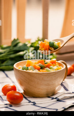 Siviera di vapore fresco raccolte verdure giovani compresi crinkle tagliare le carote affettate, piselli e patate per un sano accompagnamento a cena Foto Stock