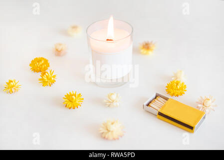 Lo stoppino in legno candela con fiammiferi e fiori di colore giallo. Elegante decorazione della casa. La masterizzazione di cera di candela profumata Foto Stock