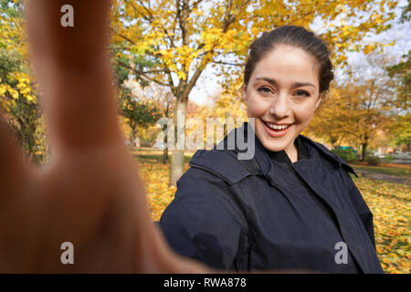 felice giovane donna scattando foto selfie nel parco con colori autunnali Foto Stock