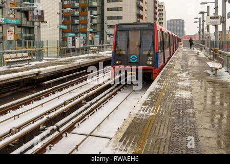 Londra, Inghilterra - Dicembre 2017. La neve cade su DLR un treno in avvicinamento East India dalla stazione di pioppo. Foto Stock