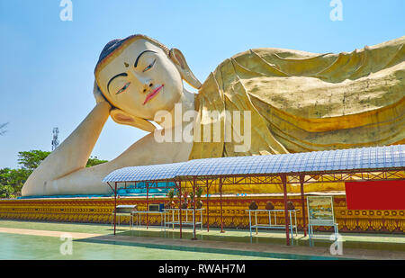 A piedi attorno al Grande Buddha reclinato immagine in Mya Tha Lyaung Tempio del Buddha, circondato da un lussureggiante giardino, Bago, Myanmar. Foto Stock