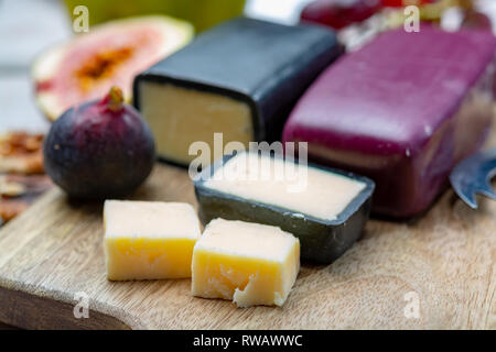 Mini nero e rosso scuro cerata formaggi cheddar realizzato da ovest paese latte e secolare e metodi in Inghilterra da vicino Foto Stock