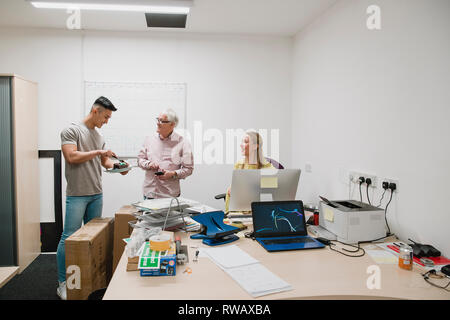 I colleghi sono di celebrare un compleanno in ufficio e sono ripartire la torta al cioccolato. Foto Stock