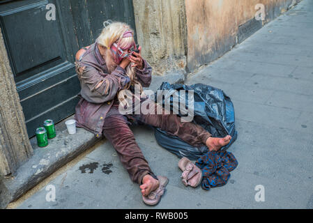 Roma - Giugno 18, 2014 : Una donna senzatetto bevande birra e mette sul make-up. Senior povera donna è seduta sul pavimento. Foto Stock