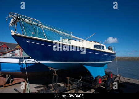 Un piccolo yacht a vela su un rimorchio al di fuori dell'acqua sul fronte del porto a Anstruther Fife Scozia UK Foto Stock