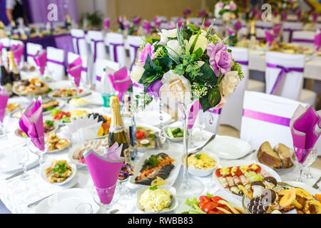 GRODNO, Bielorussia - Maggio 2014: splendidi fiori su una cena elegante tavolo in giorno di nozze. Decorazioni servita sulla tavola festiva in sfondo viola Foto Stock
