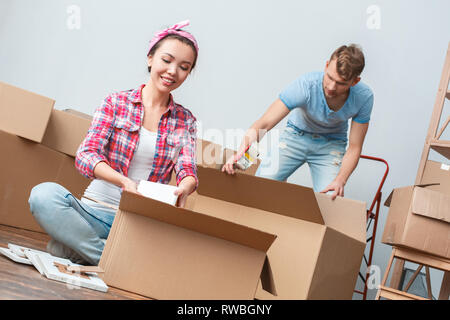 Giovane marito e moglie spostando al posto nuovo imballaggio concentrato gioioso sorridente Foto Stock
