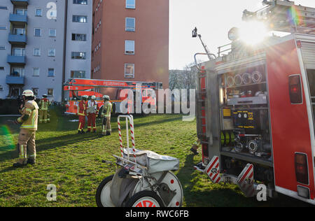 Berlino, Germania. 06 Mar, 2019. Due camion fuoco e i vigili del fuoco sono in piedi nel giardino di fronte ad un edificio alto. Sullo sfondo di un uomo è in piedi sulla via di fuga in caso di incendi. In linea di Wendland ha essa bruciato nel 3° OG da ancora inspiegabile motivo. Un uomo è stato ucciso nel processo. Un uomo ferito è già stato portato in ospedale. Un altro saranno trattati nel sito. Credito: Annette Riedl/dpa/Alamy Live News Foto Stock