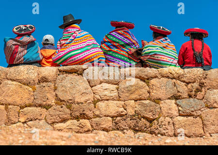 Peruviano indigeni Quechua donna in abiti tradizionali con un ragazzo seduto su un antico muro Inca in rovina di Chinchero, provincia di Cusco, Perù. Foto Stock