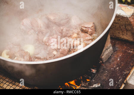 Pezzi di agnello con cipolla ebollizione in un calderone. Preparazione della zuppa Chorba, pasto tradizionale per molte cucine nazionali Foto Stock