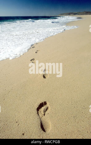 Orme nella sabbia in fuga il surf Foto Stock