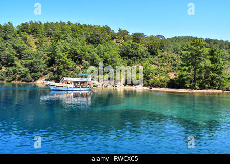 Barca ormeggiata in una bellissima baia circondata da capre, caicco crociera in barca, il Mare Mediterraneo, Turchia Foto Stock