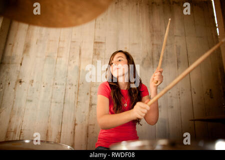 Ragazza adolescente a suonare la batteria durante la pratica di banda. Foto Stock