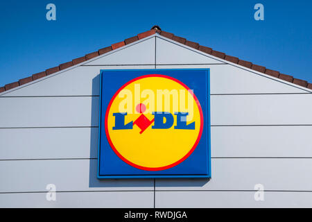 Il segno di Lidl e il logo contro un luminoso cielo blu sulla parte anteriore del negozio Lidl a Farnham, Surrey. Foto Stock