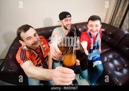 Giovani uomini bere birra e mangiare patatine e radice per il calcio. Foto Stock