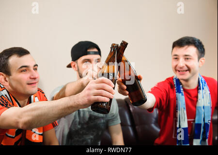 Giovani uomini bere birra e mangiare patatine e radice per il calcio. Foto Stock