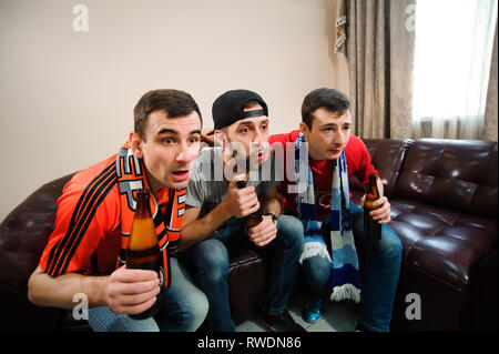 Giovani uomini bere birra e mangiare patatine e radice per il calcio. Foto Stock