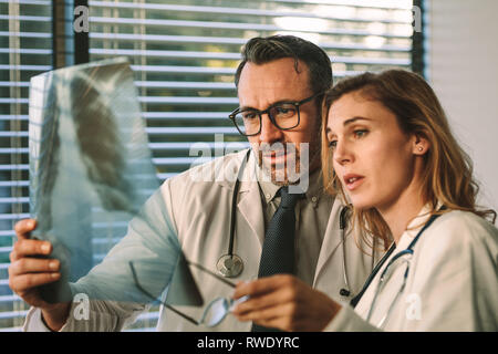 Team di medici cerchi a raggi x e la ricerca per il problema. I colleghi medici guardando film a raggi x e la diagnosi di malattia del paziente in hospita Foto Stock