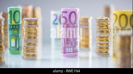 Arrotolate le banconote e le monete in euro torri impilati in altre posizioni. Foto Stock