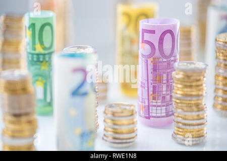Arrotolate le banconote e le monete in euro torri impilati in altre posizioni. Foto Stock