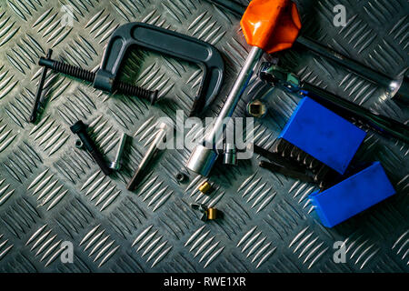 Vista superiore di utensili in metallo industriale checker piastra. In metallo per checkerplate anti skid. Il dado, le viti e la chiave esagonale sul foglio di metallo piano. Argento bump polv Foto Stock