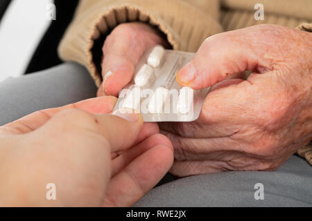 Close up foto di donne anziane ricevere medicinali dal caregiver maschio - home care, assistenza, aiuto Foto Stock