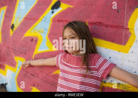 Bellissima fanciulla contro un variopinto muro di graffiti, Spagna Foto Stock