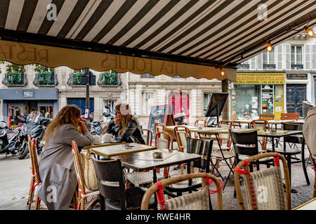 Due donne sedute fuori ad un tavolo in un ristorante parigino a St Georges, nel 9° Arrondissementt di Parigi, Francia Foto Stock