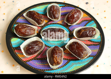 Tettuccio di colpo di Medjool date su una piastra circolare. Cibo colorato Mandala Foto Stock