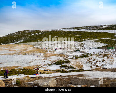 Irriconoscibile persone scivolando sul ghiaccio in un pendio in montagna su La Covatilla, Bejar (Salamanca) Foto Stock