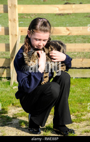 Una ragazza di scuola volontario con un Manx cat (senza una coda) al Mann Cat santuario sulla isola di Man Isola di Man con la sua capitale, Douglas Foto Stock