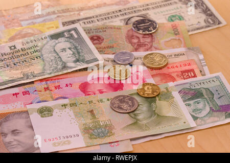 Varie banconote provenienti da diversi paesi steso sulla tavola con alcune monete sulla parte superiore - moneta, denaro, banconote, valute del mondo, contanti Foto Stock