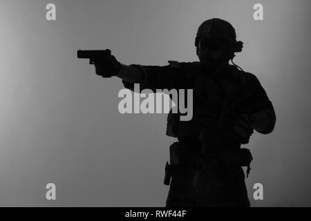 Silhouette di U.S. Marine Corps Marsoc raider pistola di puntamento e sfondo grigio. Foto Stock