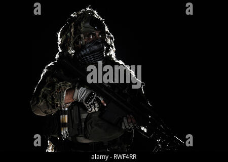 Army Sniper con faccia dipinta, tenendo un grande fucile. Foto Stock