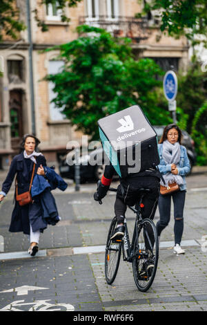 Parigi, Francia - Sep 12, 2017: vista posteriore del ciclista Deliveroo fast ciclismo su strada francese a fornire alimenti con vicino a donne in cammino Foto Stock