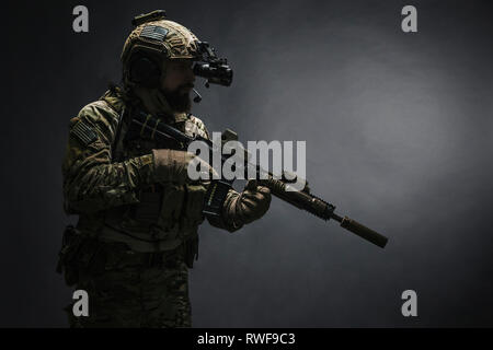 Barbuto soldato in uniforme di combattimento con arma, studio shot. Foto Stock