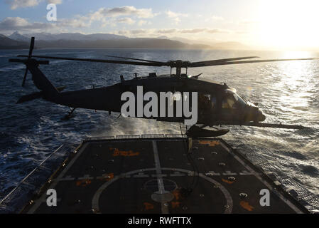 Un Alaska Air National Guard UH-60G Pave Hawk elicottero si libra sopra il ponte di volo del guardacoste Alex Haley (WMEC 39) per preparare una formazione congiunta di esercitare con la Guardia Costiera della sicurezza marittima la risposta del team di West di soci in Chiniak Bay, Alaska, Feb 23, 2019. I membri del team sono istruiti e sono tecnicamente competente in tecniche avanzate con federali, statali e i partner locali per proteggere la nazione da minacce sia in mare e in aria. Stati Uniti Coast Guard foto di Sottufficiali di terza classe Lauren Dean. Foto Stock